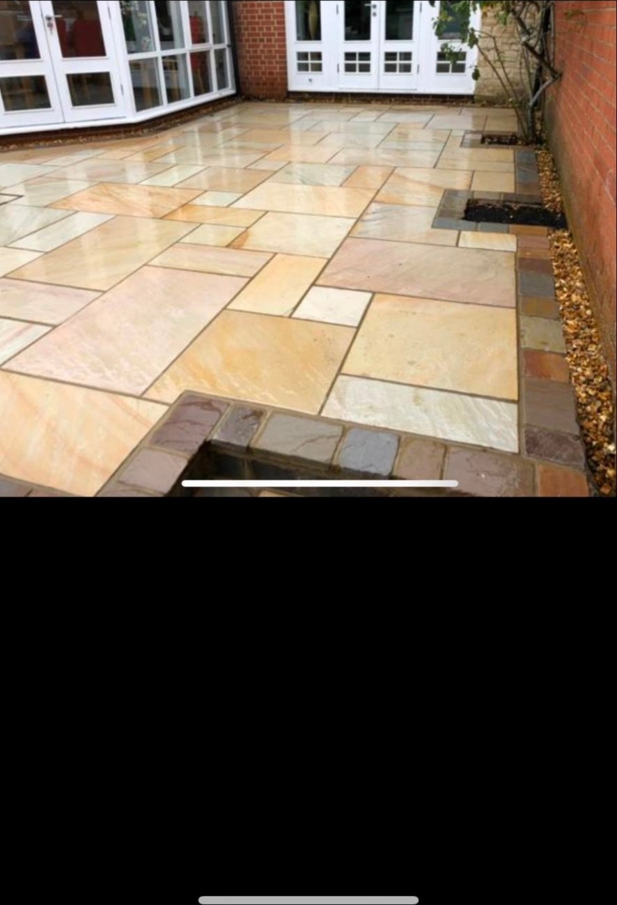 Sandstone flagstone patio with natural stone borders and gravel drainage edge.