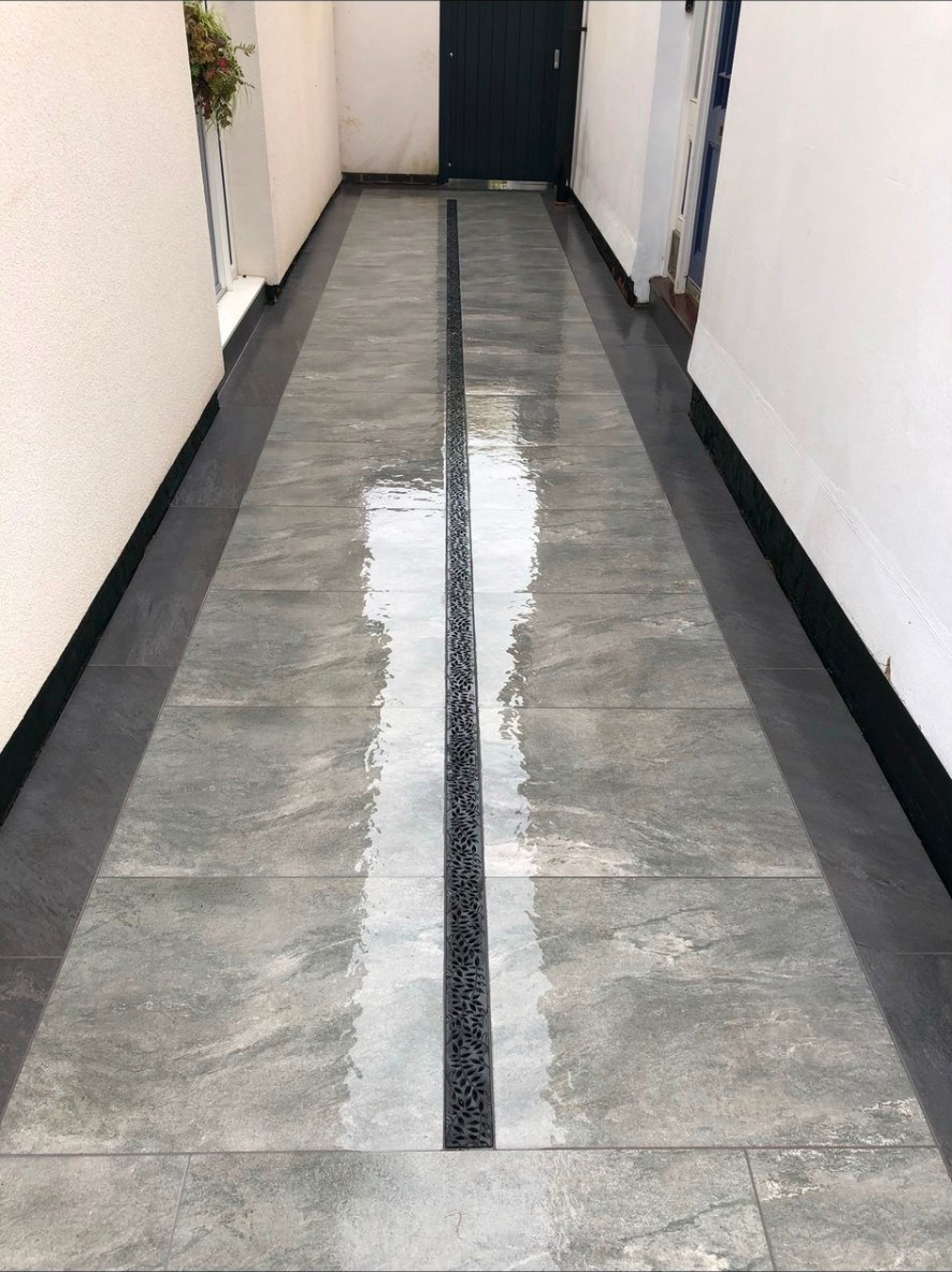 Contemporary grey porcelain paving path with central decorative drainage channel in a side return