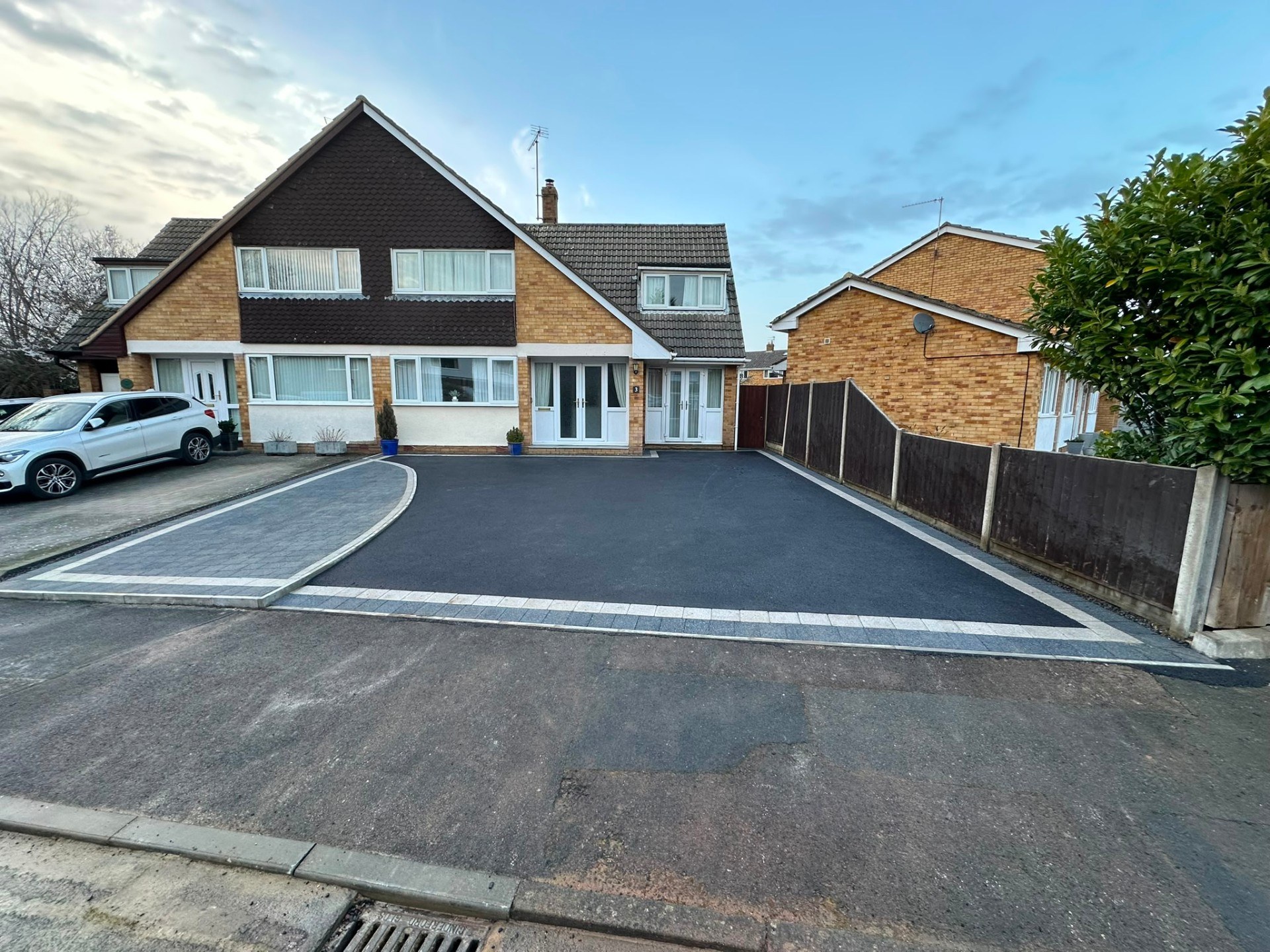 Modern tarmac driveway with decorative block-paving border and matching curved parking bay.