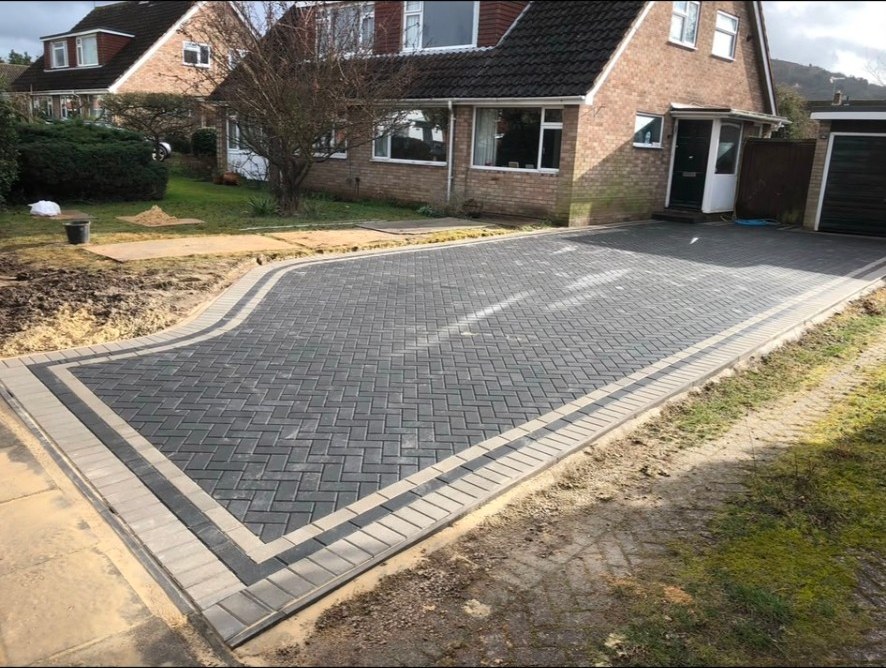 Dark grey herringbone block paving driveway with light grey decorative border