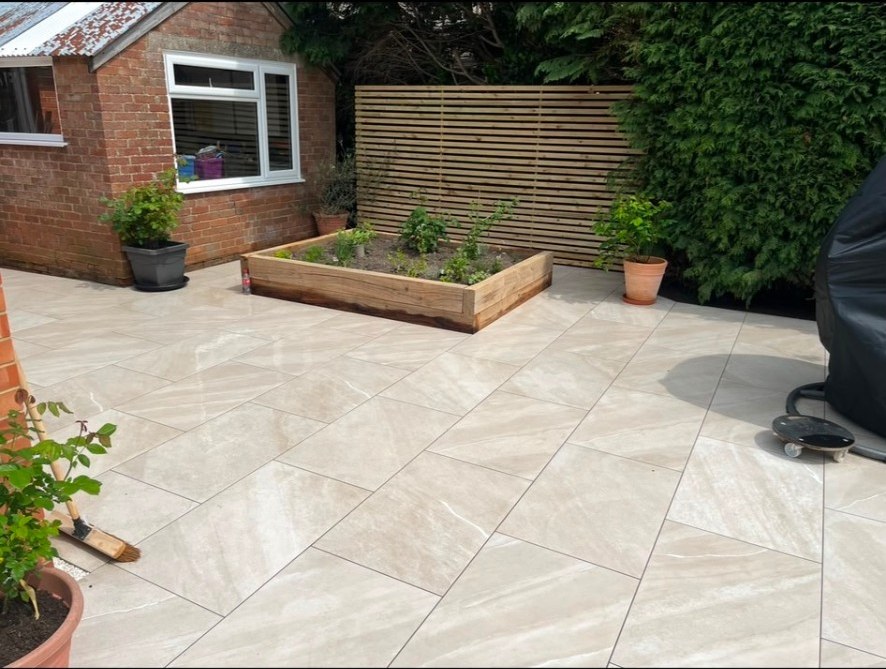 Contemporary beige porcelain tiled patio with timber raised planter and slatted fencing.