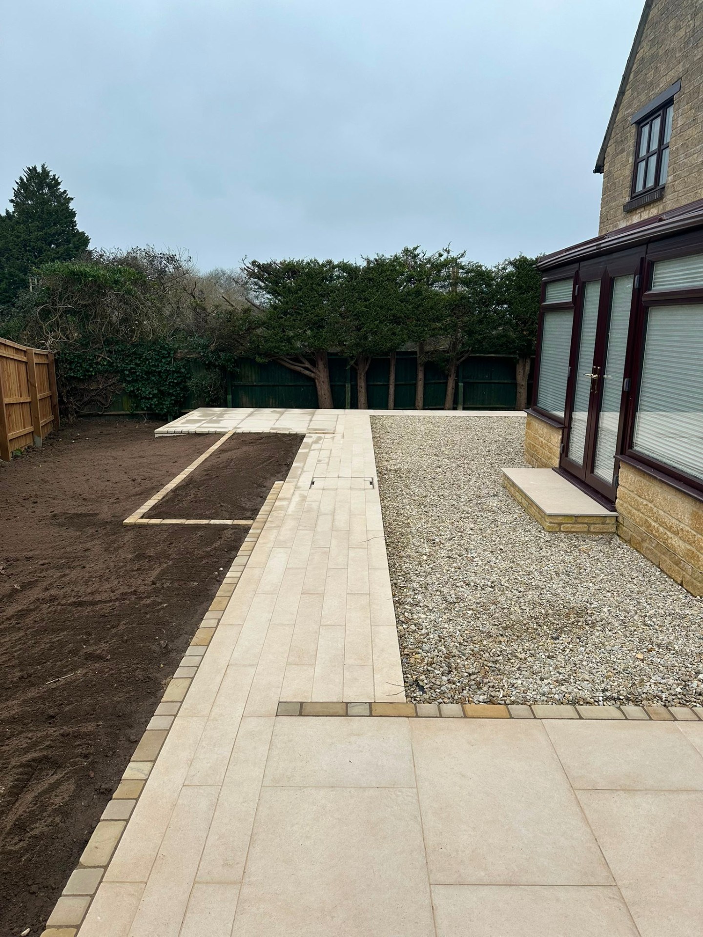 Modern garden landscaping with light porcelain paving, decorative gravel, and new flower beds.