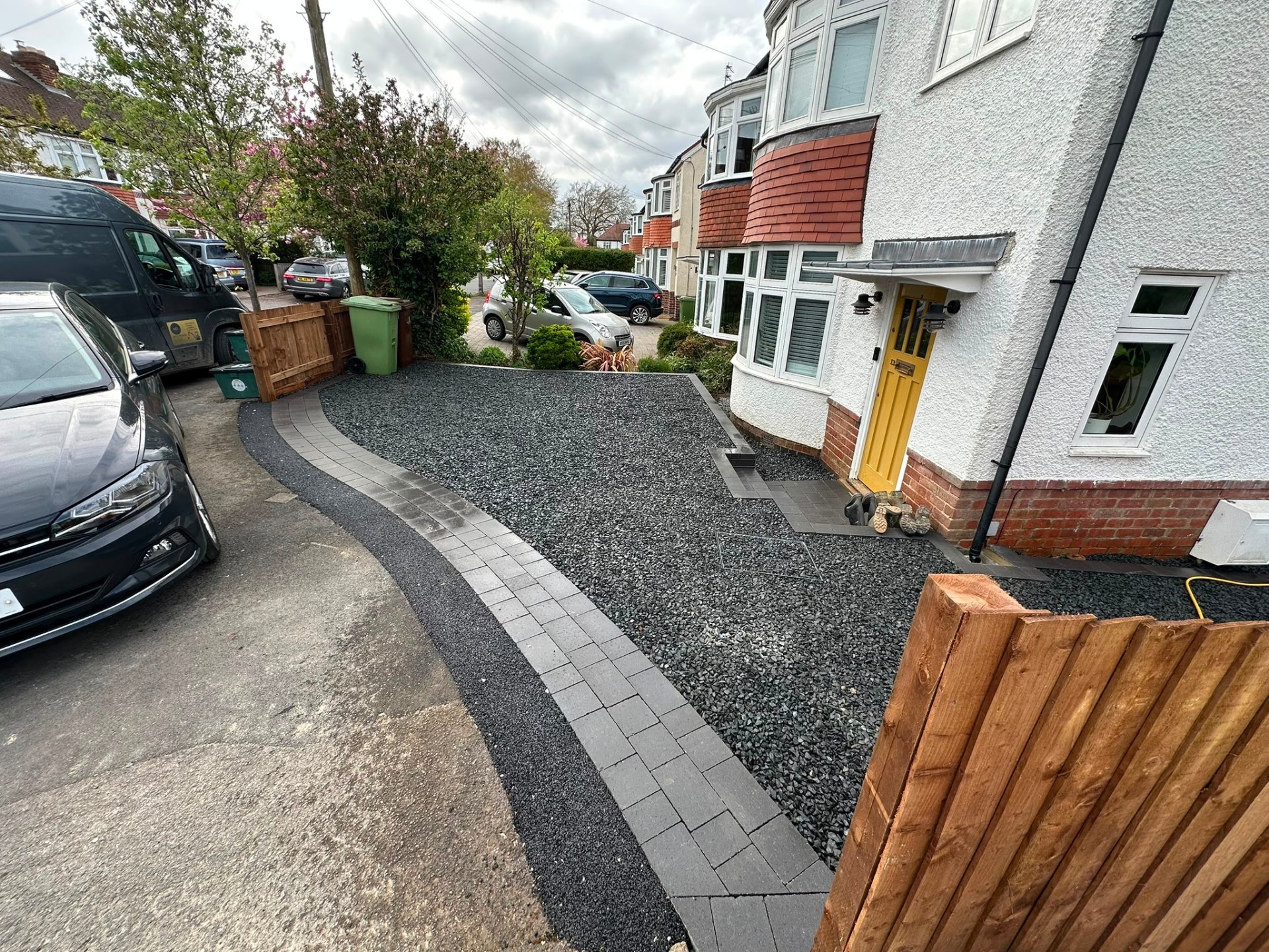 Dark grey gravel driveway with curved block paving border and matching doorstep.