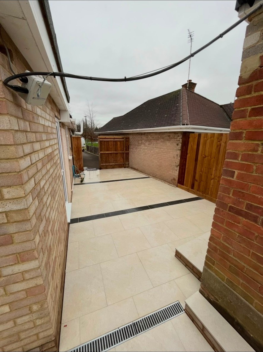 Contemporary cream porcelain patio with dark grey feature strips and integrated drainage.