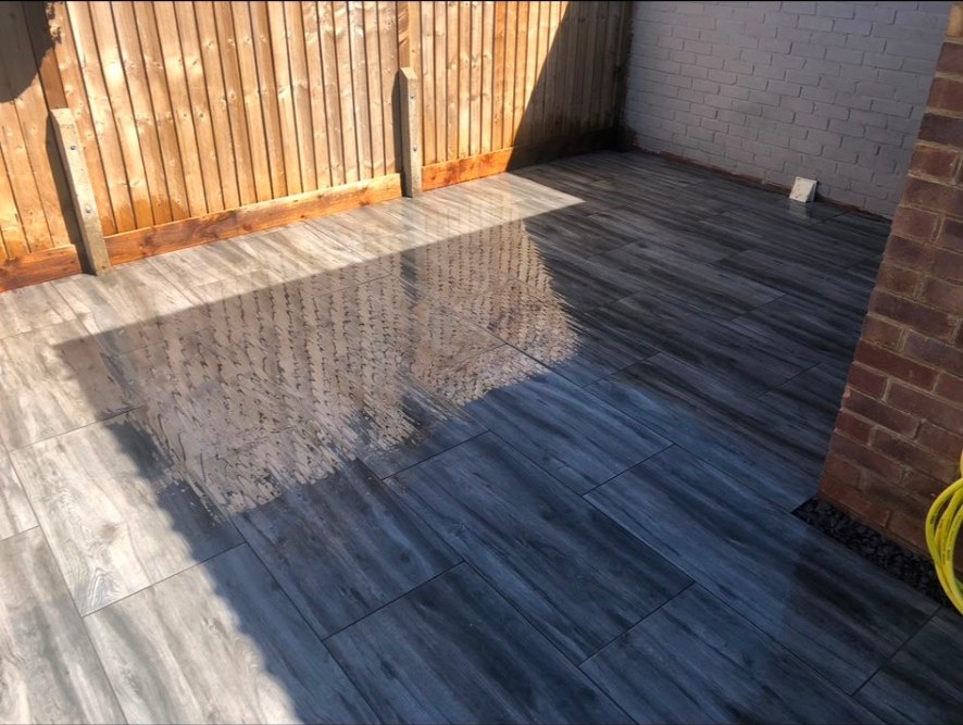 Contemporary wood-effect porcelain paving on a garden patio with timber fencing.