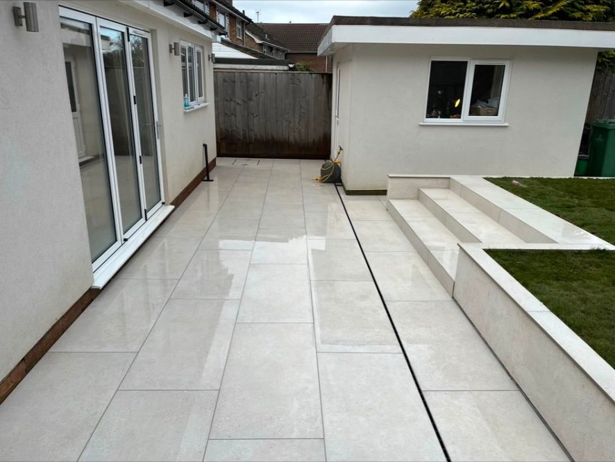 Contemporary light grey porcelain patio with matching steps and integrated drainage