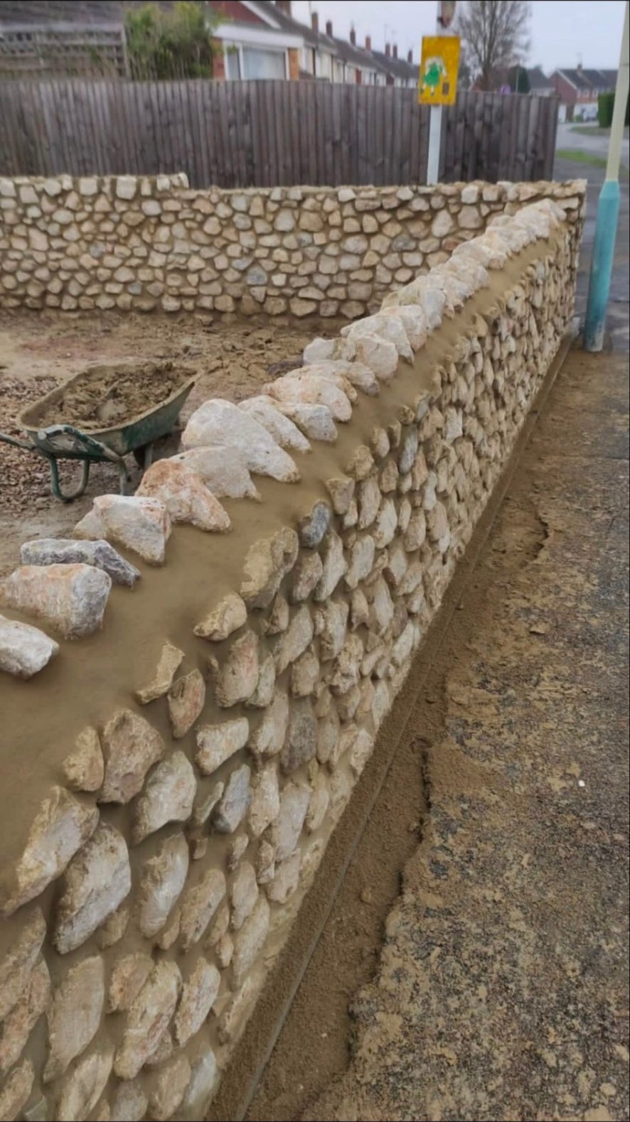 Dry stone wall construction with Cotswold stone and mortar capping.