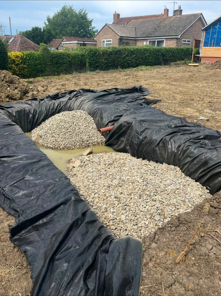 Groundworks showing drainage pipe installation and gravel soakaway with weed membrane.